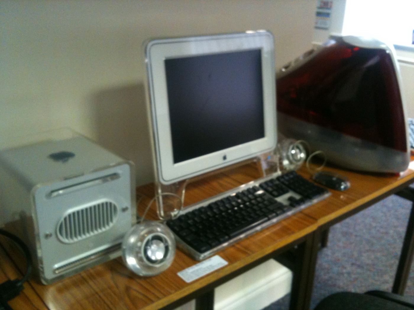 The Power Mac G4 Cube alongside an iMac G3 in graphite color, both designed by Jonathan Ive