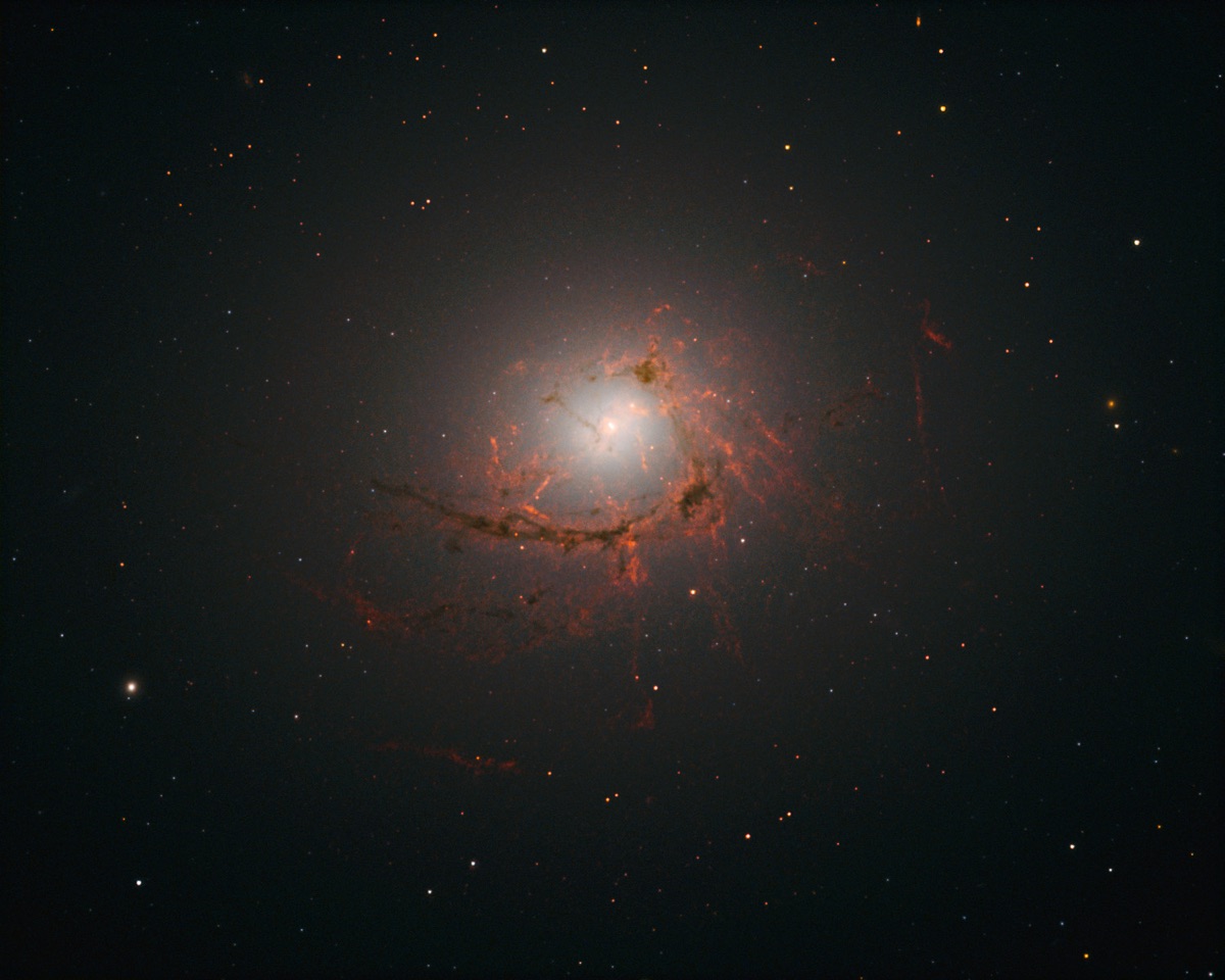 Hubble Space Telescope image of NGC 4696, the central galaxy of the Centaurus Cluster, showing delicate dusty filaments of gas curling inward toward its central supermassive black hole.