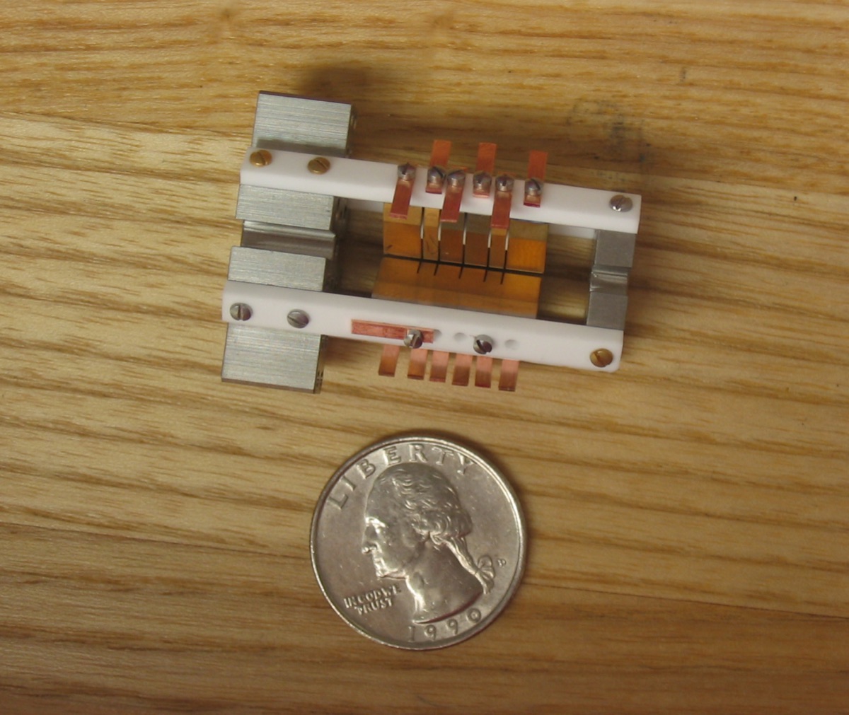 An ion-trap device from a NIST aluminum-ion quantum logic clock, shown with a coin for scale, used to illustrate the kind of quantum system in which physicists reshaped the arrow of time.