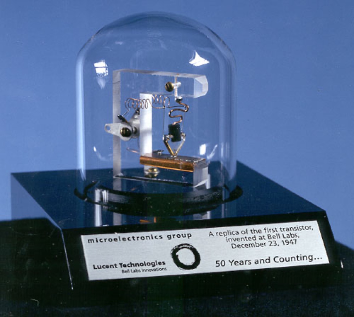 A replica of the first working transistor - the point-contact transistor built by John Bardeen and Walter Brattain at Bell Labs in December 1947 - showing two gold contacts pressed onto a small germanium crystal. Public domain, via Wikimedia Commons.